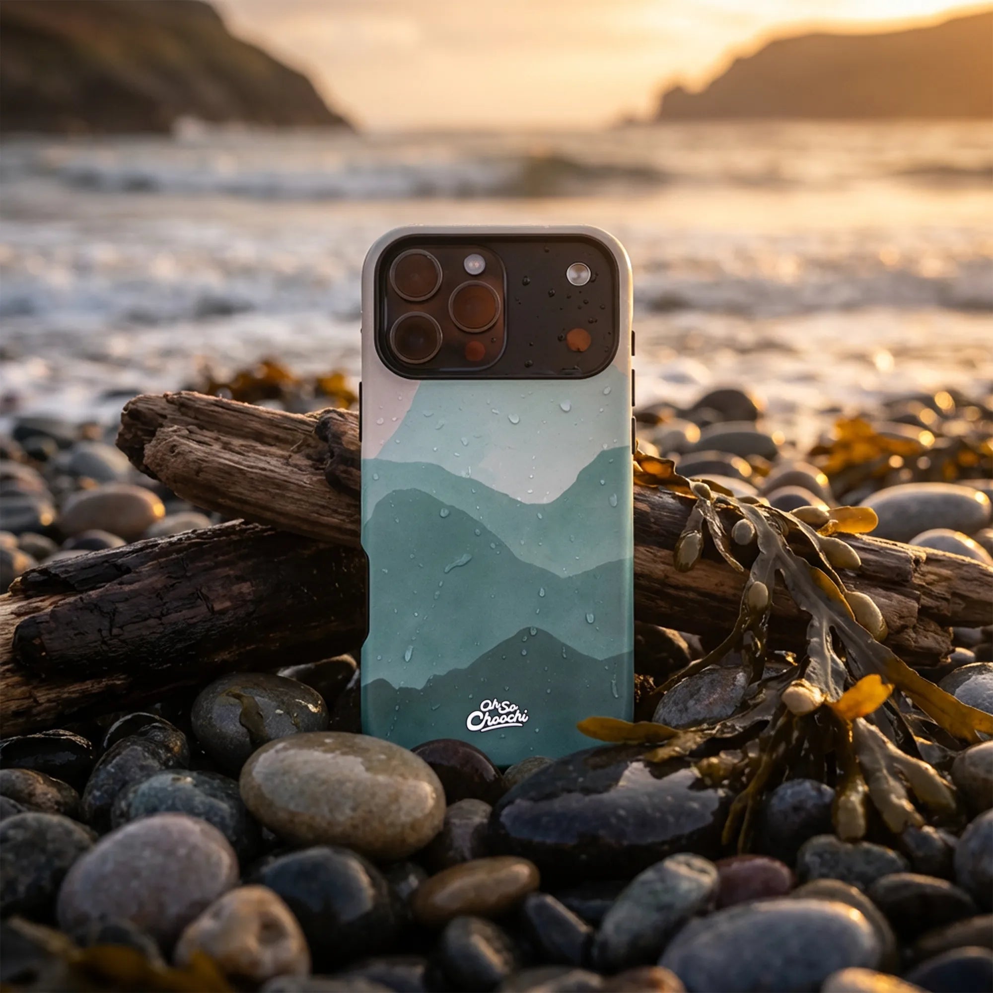 Phone case with mountain design on a pebbly beach at sunset